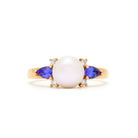 A product photo of a rose gold ring with a rosaline pearl in the centre, hugged by a tanzanite and two diamond jewels on either side.