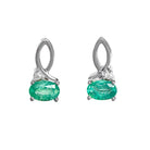 A product photo of a pair of emerald and diamond earrings in 9k white gold on a white background. The 6x4mm emeralds are horizontally-oriented, and hang by elegant loops of white gold - decorated with a single white diamond on the outer edge of each earring.