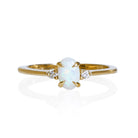 A product photo of a delicate 9ct yellow gold 6x4mm white opal and diamond trio ring sitting on a white background. The fiery opal centre stone is hugged on either side by a bright white diamond jewel.