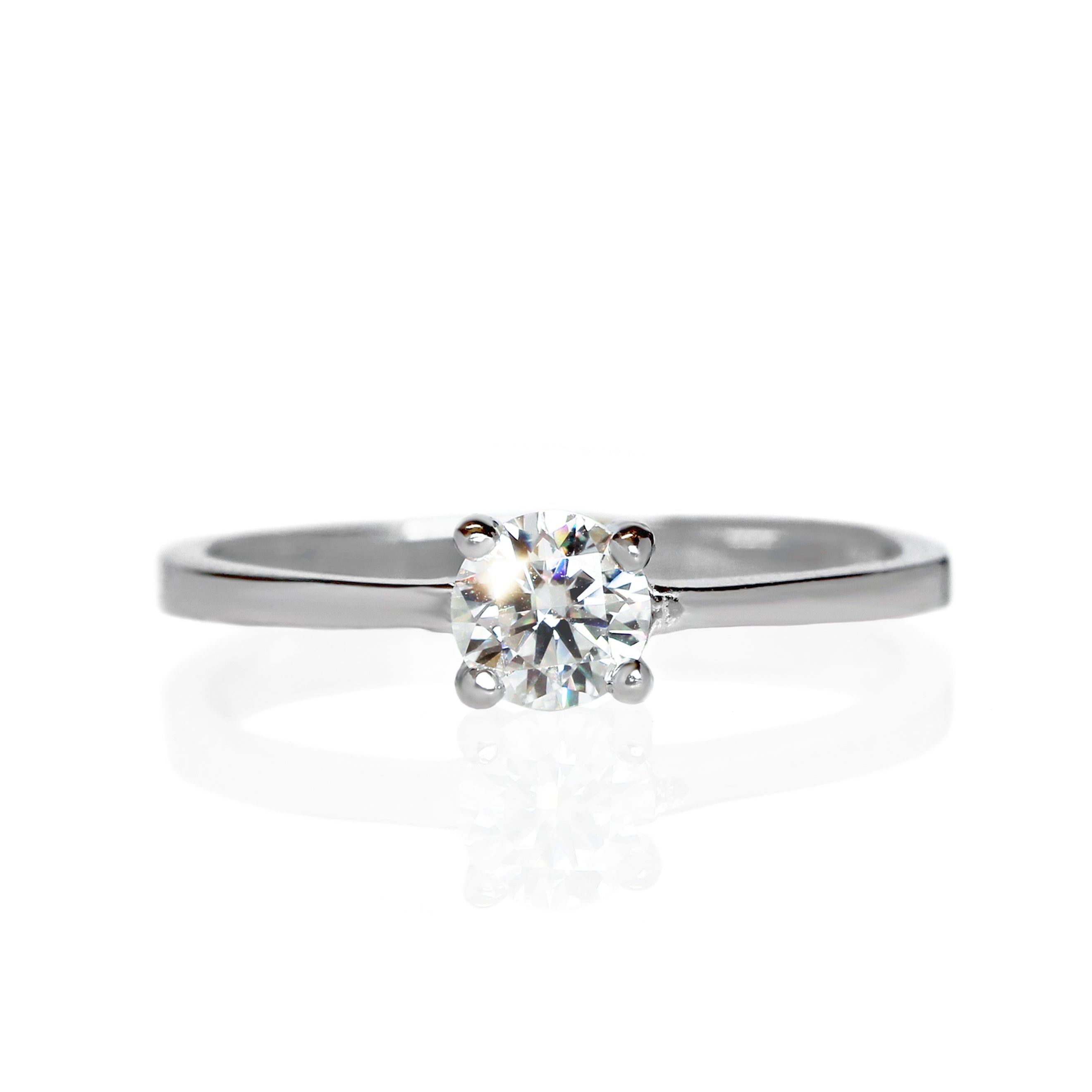 A product photo of a moissanite solitaire ring in 925 sterling silver sitting on a clear white background. A single reflective moissanite gem sits in the centre of the smooth silver band, held securely in place by 4 delicate claws.