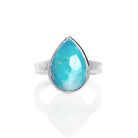 A product photo of a silver Larimar ring on a white background. The band is tall and thick. The 12x8mm pear cabochon Larimar stone has dappled white and light blue patterning, similar to water reflections at the bottom of a pool. The stone is set in a thick silver bezel setting.