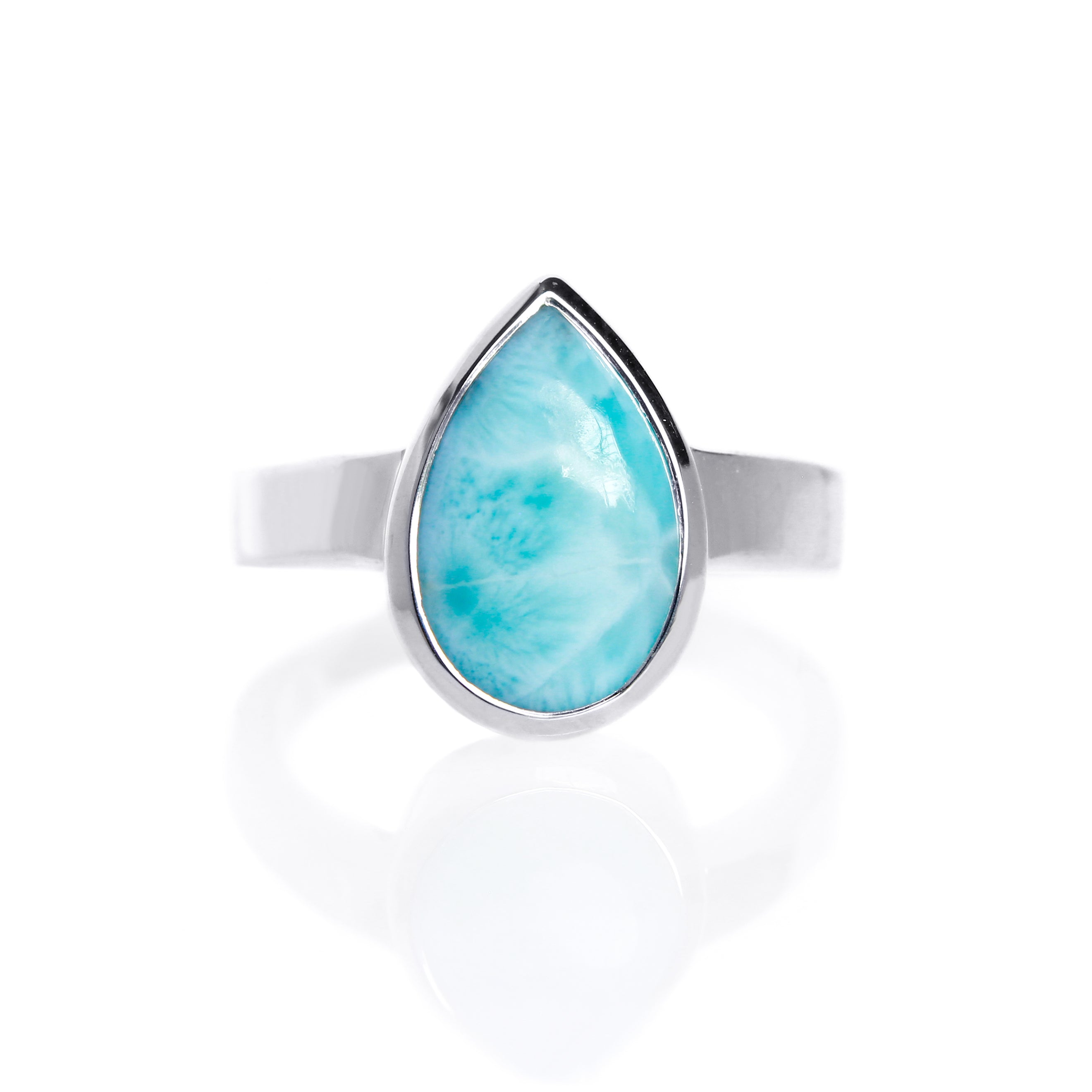 A product photo of a silver Larimar ring on a white background. The band is tall and thick. The 14x9mm pear cabochon Larimar stone has dappled white and light blue patterning, similar to water reflections at the bottom of a pool. The stone is set in a thick silver bezel setting.