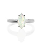 A product photo of a silver rainbow opal solitaire ring on a white background. The 12x6mm marquise-shaped faceted opal stone is uniquely translucent, with a light base tone and rainbow-coloured fire. The stone is held in place with 4 silver claws.