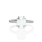 A product photo of a silver moonstone solitaire ring on a white background. The 9x7mm oval faceted moonstone is uniquely translucent, with an indigo sheen and milky inclusions. The stone is held in place with 4 v-shaped silver claws.