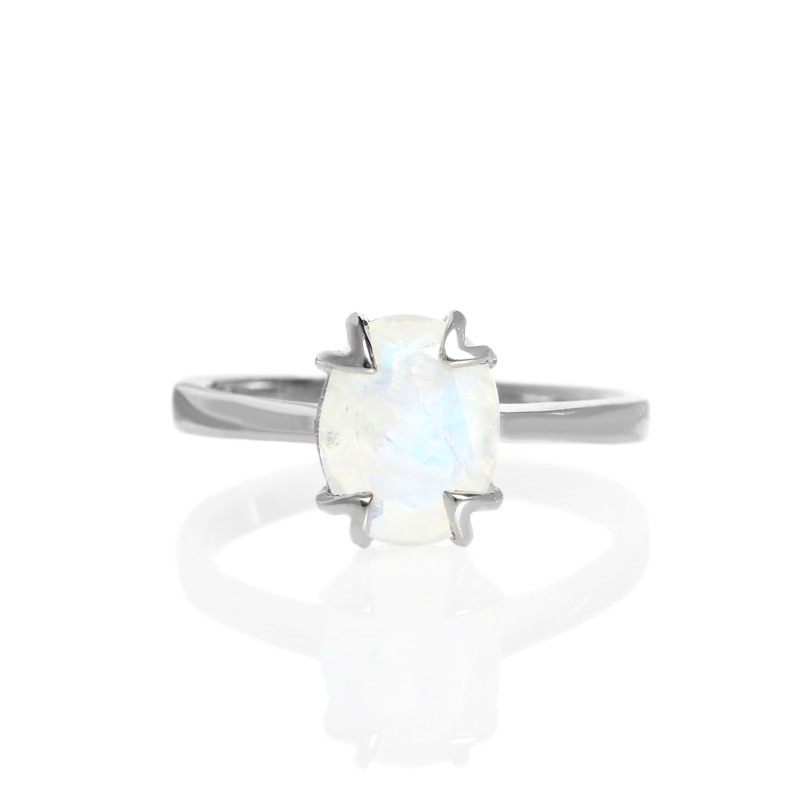 A product photo of a silver moonstone solitaire ring on a white background. The 9x7mm oval faceted moonstone is uniquely translucent, with an indigo sheen and milky inclusions. The stone is held in place with 4 v-shaped silver claws.