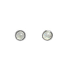 A product photo of a pair of silver moonstone stud earrings sitting against a white background. The 5mm round gemstones have a grey and blue sheen and unique milky inclusions, and are secured in place in bezel settings.