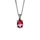 A product photo of a silver pink tourmaline pendant suspended by a silver chain against a white background. The oval gemstone is held in place by 4 small claws, and reflects deep magenta hues from its many edges