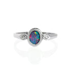 A product photo of an unusual opal doublet and moissanite ring. The 7x5mm doublet is wrapped in a frame of silver.