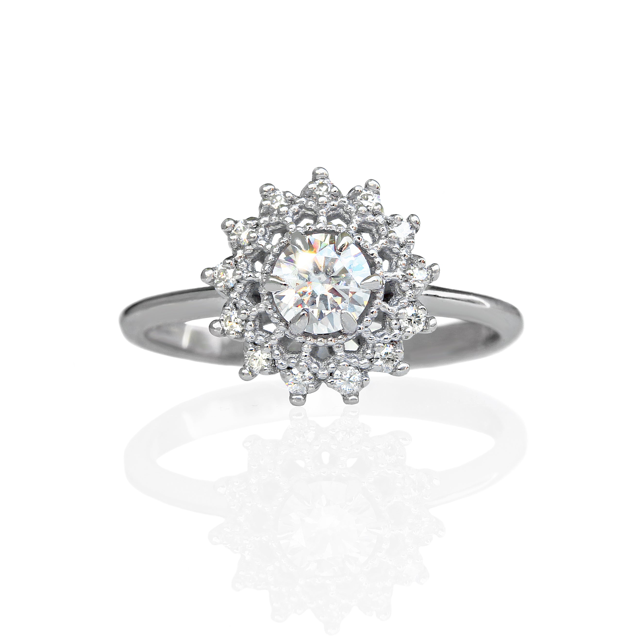 A product photo of a moissanite halo and filigree detailed engagement ring in solid 925 sterling silver. The ring consists of a 4.5mm round dazzling white moissanite centre stone, which is framed by ornate, almost spiderweb-like silver filigree halo detailing, with the very tip of each detail punctuated by a tiny sparkling 0.01ct moissanite jewel.