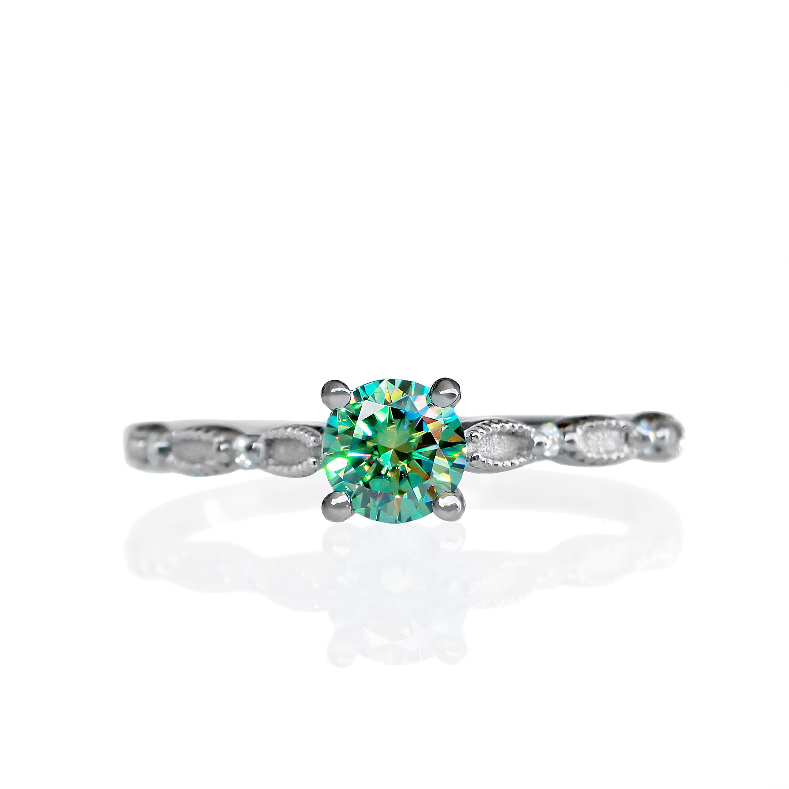 A product photo of a mint green colour moissanite engagement ring on a white background. The ring consists of a single 5mm round mint green moissanite centre stone, reflecting rainbow colours in the light, and 4 0.01ct white moissanite details studded along its filigree-detailed silver band.