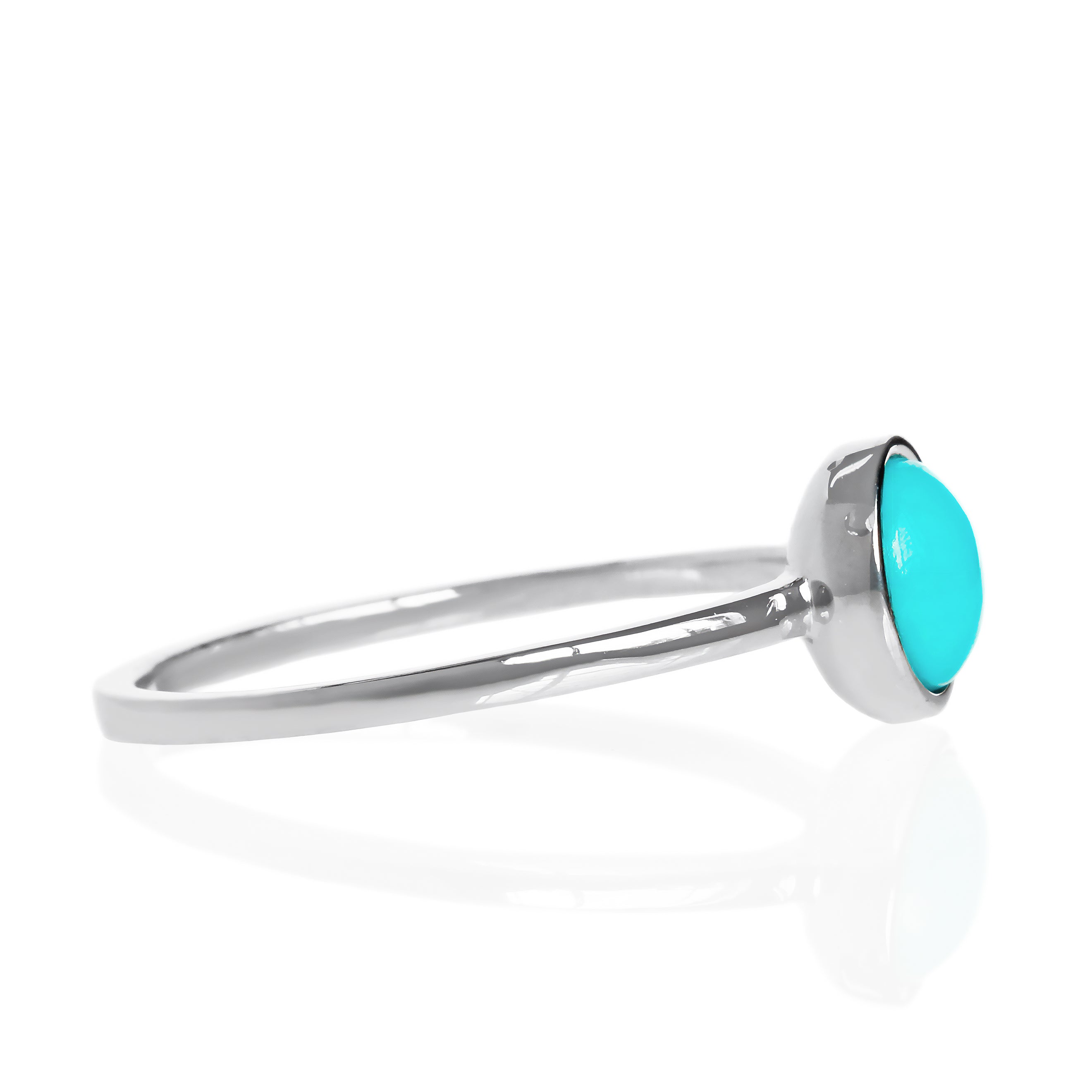 A product photo of a turquoise silver solitaire ring on a white background. The ring consists of a singular 6mm round cabochon-cut gem encased in a layer of silver bezel setting. The blue turquoise stone hails straight from the Sleeping Beauty mountains of Arizona. The band is simple and smooth silver metal. 