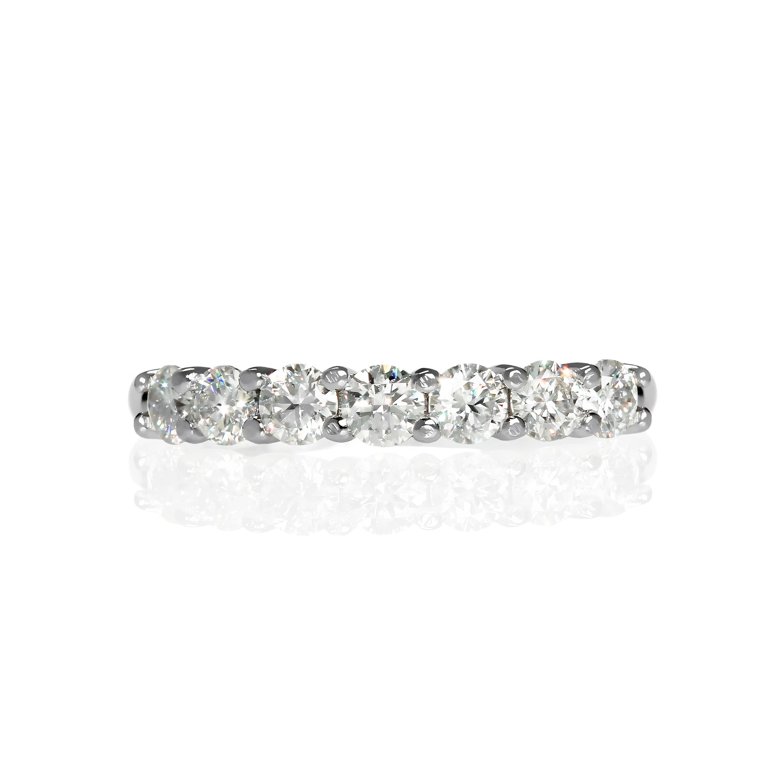 A product photo of a bold half-eternity stacking ring in 9k white gold – made up of 7 3mm white moissanite jewels – sitting on a white background.