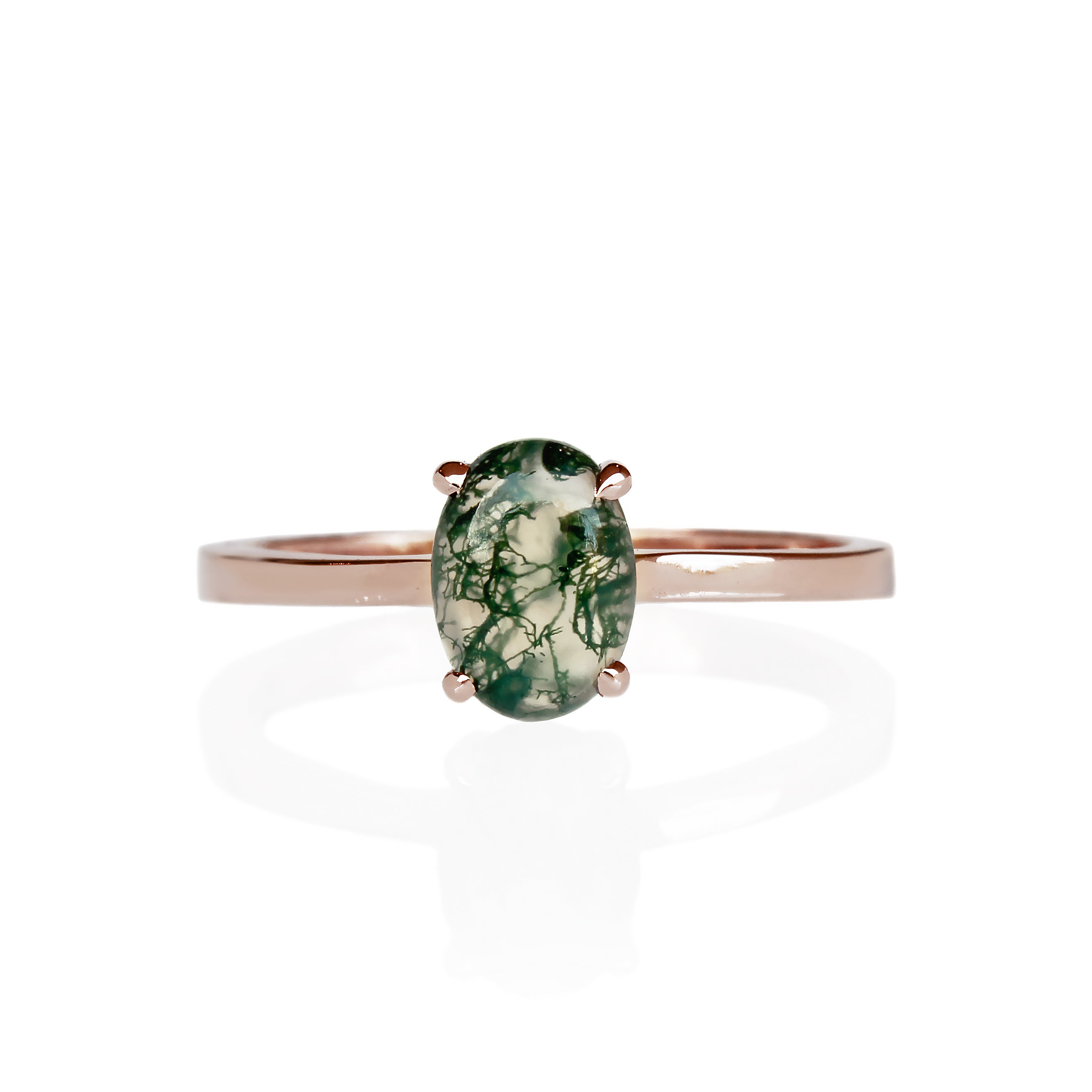 A product photo of an oval rose gold solitaire ring on a white background. The band is rounded and smooth, and the 7x5mm cabochon moss agate is held in place by 4 delicate rose gold claws.