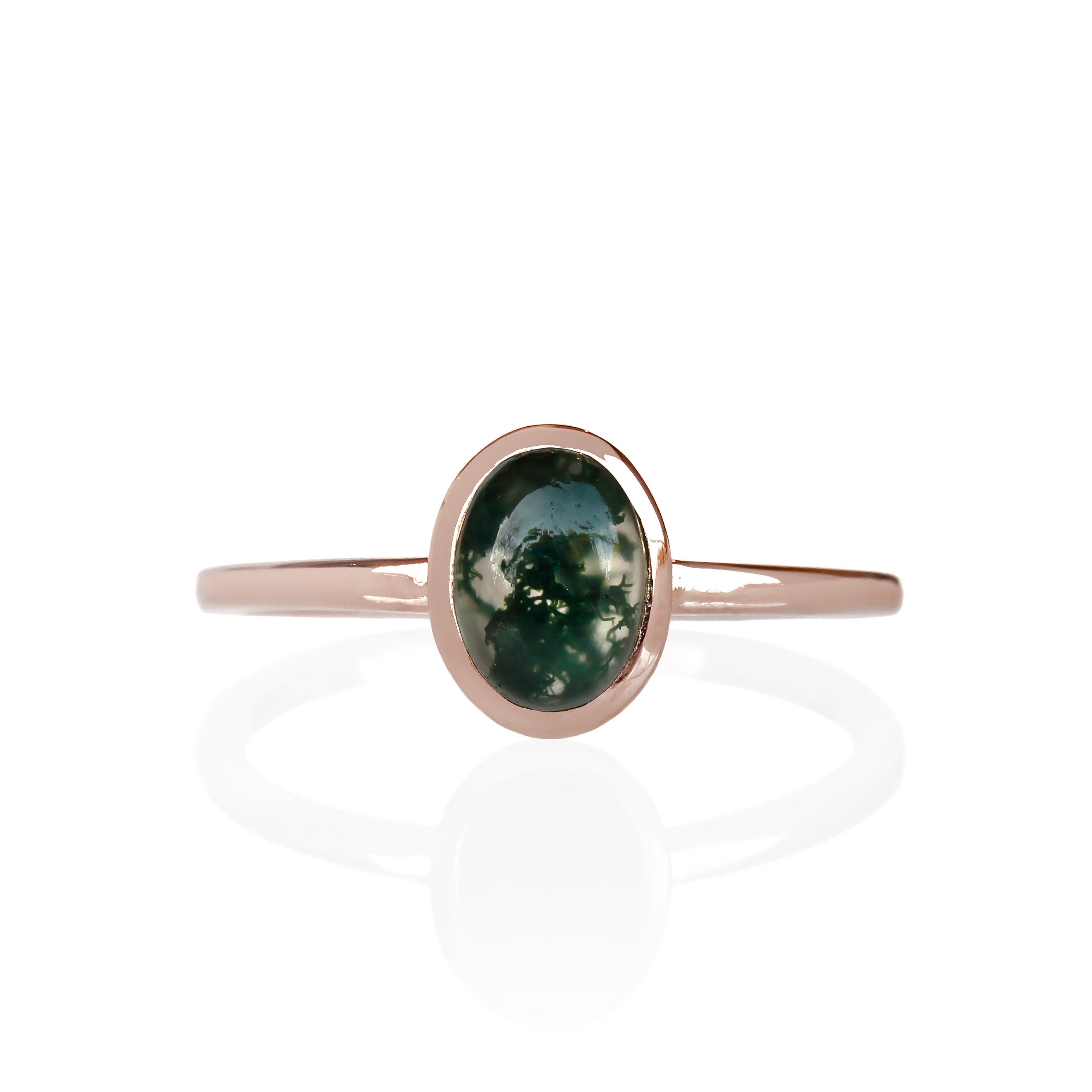 A product photo of a cabochon moss agate solitaire ring in 9 karat rose gold on a white background. The cabochon cut stone is held in place by a delicate bezel setting.