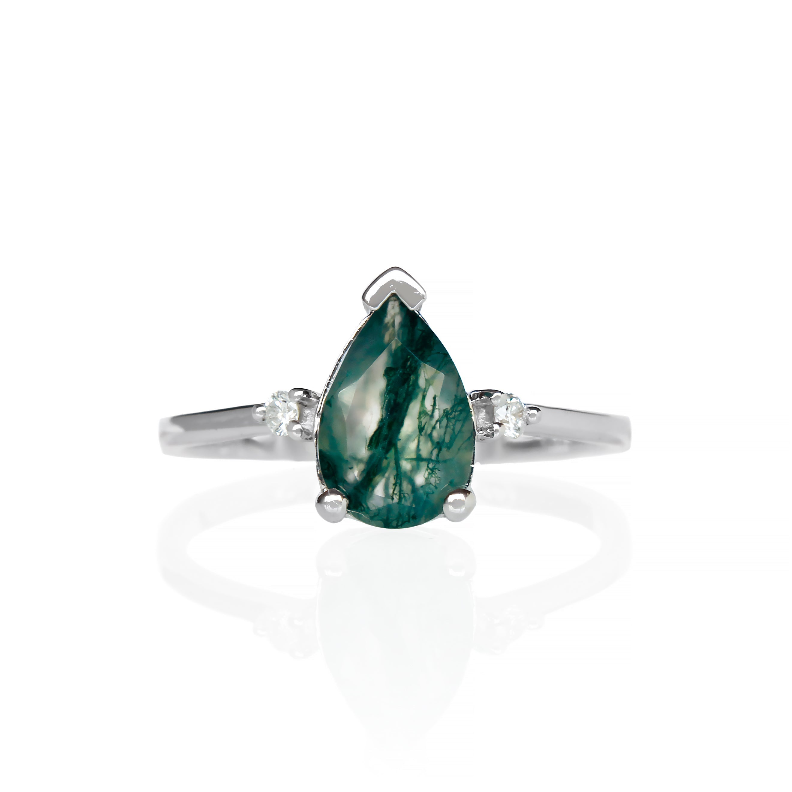 A product photo of a 9 karat white gold ring with a pear-cut moss agate centre stone sitting on a white background. The golden band is simple and smooth, meeting elegantly on either side of the centre stone, hugged by a single white diamond on either side.