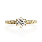 A product photo of a simple lab-grown diamond engagement ring in solid 9 karat yellow gold sitting on a plain white background. The centre stone is held in place by 6 delicate claws, with light filigree detailing around the embedded laboratory diamonds along the band.