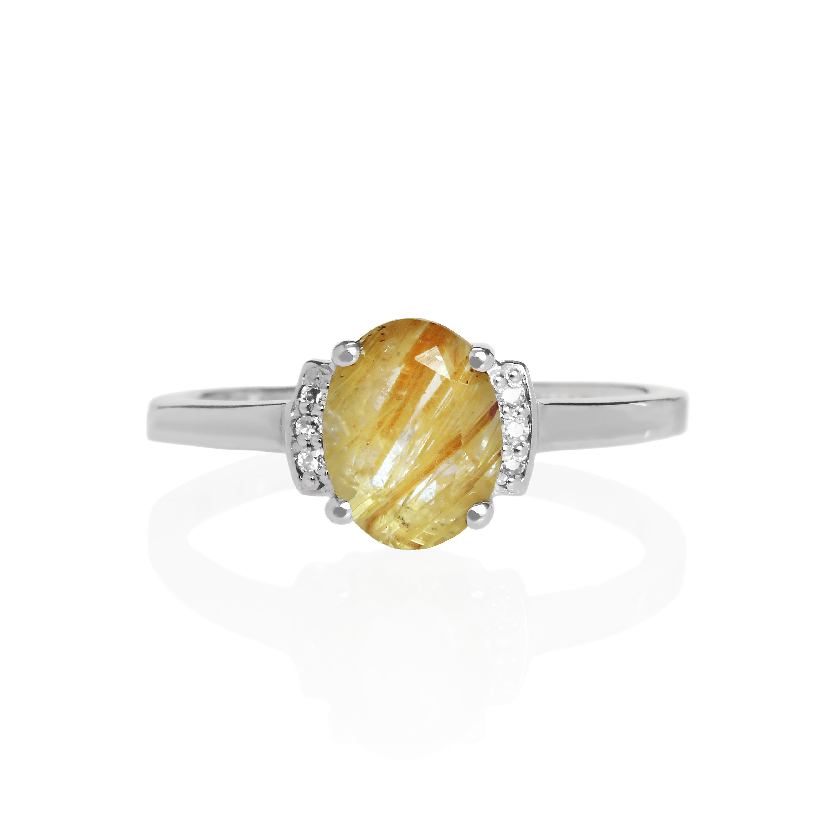 A product photo of a silver golden rutile quartz and moissanite trio ring sitting on a white background. The oval, naturally-included golden rutile quartz gemstone, featuring shimmering golden needles within the clear quartz, stands in stark contrast to the little clusters of three classic white moissanite stones on either side.