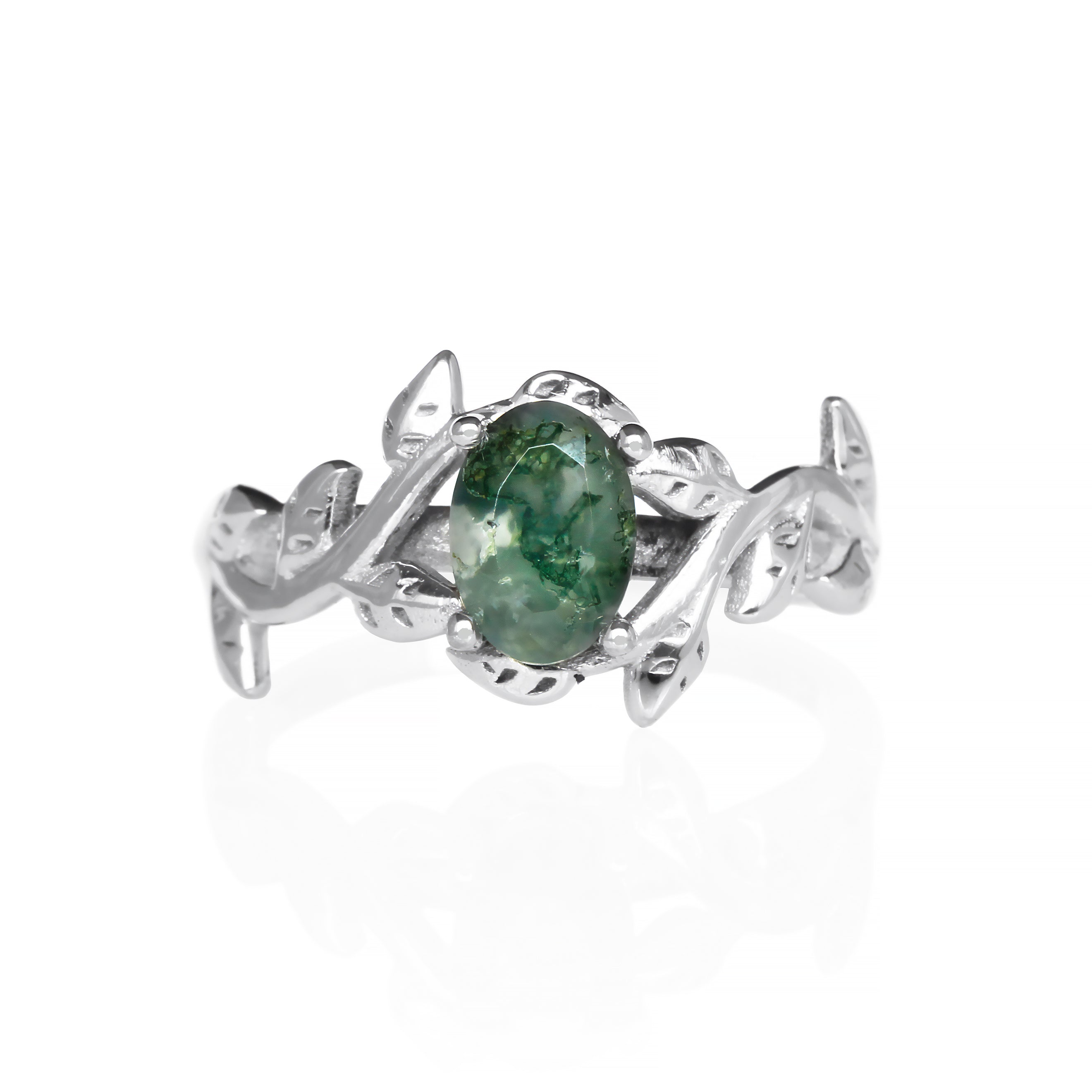 A delicate and ornate sterling silver ring featuring a 7x5mm oval moss agate center stone on a white background. The moss agate stone displays a unique pattern of green dendritic inclusions, resembling moss or lichen. The ring's intricate floral band is adorned with delicate leaf-like motifs, meticulously crafted with detailed veins and edges. Ideal for use as a promise ring, this nature-inspired piece showcases the beauty of natural gemstones and intricate craftsmanship.