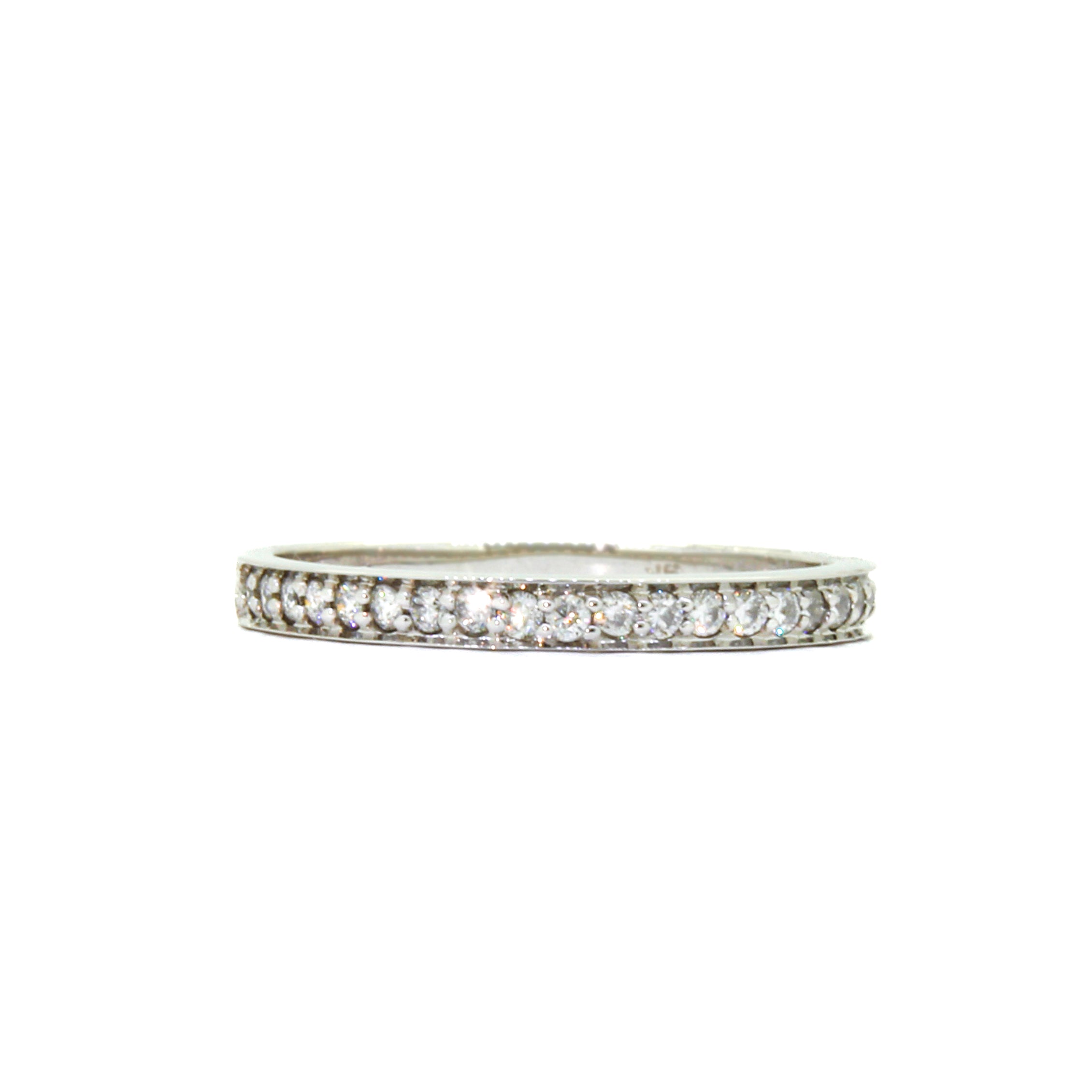 A product photo of a half eternity moissanite ring in 9k white gold sitting on a clear white background. two flat circular bands hug the top and bottom of the central band embedded with dazzling moissanite gems, all the way around.