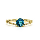 An ornate golden ring with a dazzlling centre topaz and diamond band detailing.