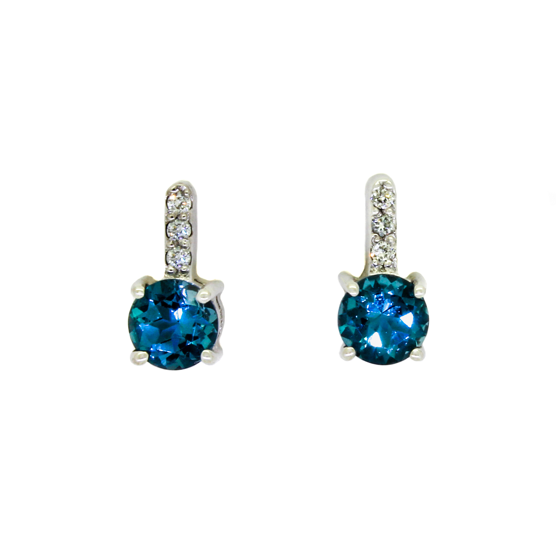 A product photo of a pair of white gold london blue topaz earrings sitting against a white background. The simple circle-cut stones are contrasted by the white diamond trio protruding in a straight line above each stone, encased in white gold.