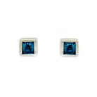 A product photo of a pair of white gold london blue topaz earrings sitting against a white background. Two deep blue topaz stones are encased in their square shapes by equally geometric squared white gold frames.