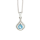 A product photo of a silver pendant with a light blue topaz centre stone. The stone sits at the base of a silver teardrop shape, with a small diamond positioned above it. The pendant is suspended by a silver chain against a white background.