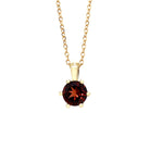 A product photo of a 5mm Round Garnet Pendant in 9k Yellow Gold suspended against a white background. The stone is held in place by 6 delicate golden claws. It is suspended by a simple gold chain. The garnet reflects sanguine hues across its multi-faceted edges.