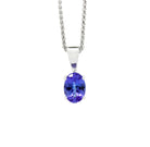 A product photo of a white gold tanzanite pendant suspended by a chain against a white background. The oval stone is held in place by 4 small claws, and reflects violet blue and indigo colours from its many edges.