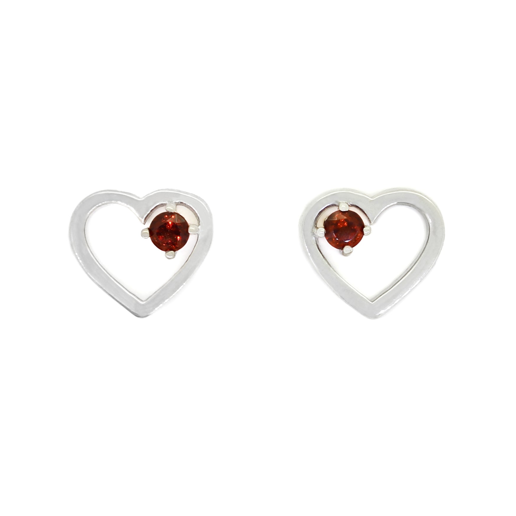 A product photo of two silver heart-shaped stud earrings sitting on a white background. A delicate, 2.5mm round red garnet is nestled in the top right corner of each heart-shaped frame.