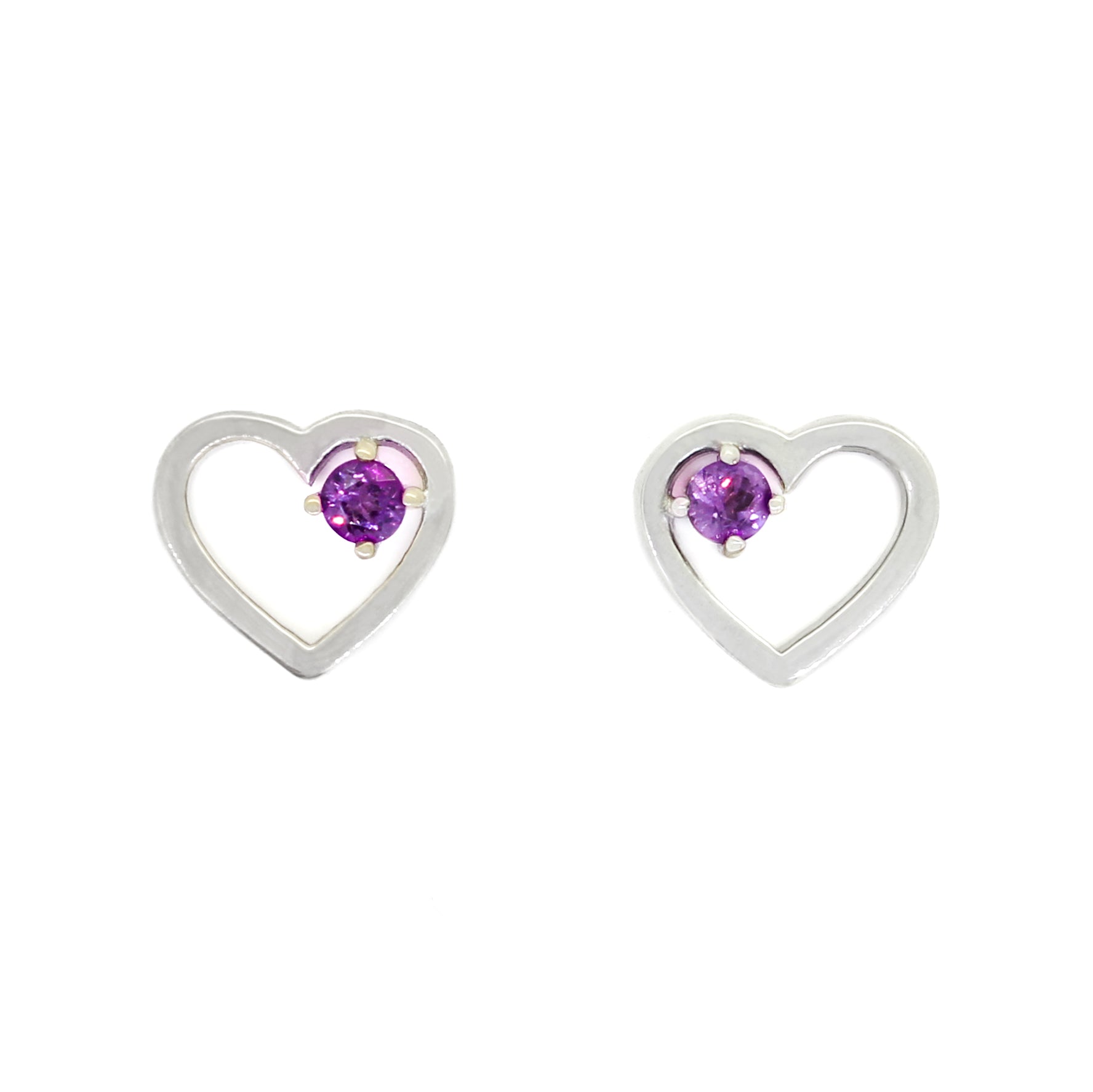 A product photo of two silver heart-shaped stud earrings sitting on a white background. A delicate, 2.5mm round purple amethyst is nestled in the top right corner of each heart-shaped frame.