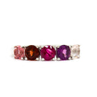 A product photo of a bold, multi-gemstone ring in 9k white gold – made up of 5 pink & red coloured jewels – sitting on a white background. From left to right, 4.5mm round-cut pink tourmaline, garnet, ruby with stunning streaked inclusions, grape garnet and morganite stones make up a boldly feminine statement piece.