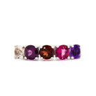 A product photo of a bold, multi-gemstone ring in 9k white gold – made up of 5 pink & red coloured jewels – sitting on a white background. From left to right, 4.5mm round-cut morganite, grape garnet, red garnet, pink tourmaline & amethyst stones make up a boldly feminine statement piece.