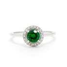 A product photo of a classic diamond halo tsavorite ring in solid 9k white gold on a white background. The diamond halo is framed by a thick band of solid 9k white gold, and the rounded band is smooth and minimalistic. The deep, verdant-green tsavorite centre stone is held in place by 4 claws and reflects light off of its many facets. The green gemstone colour would be a good emerald substitute.