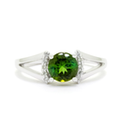 A product photo of a sophisticated  green tourmaline split-band ring with diamond framing on a white background. 4 diamonds sit on either side of the forest-green tourmaline gemstone, with the split band on either side holding the tourmaline and diamond arrangement in place. The green gemstone colour would be a good emerald substitute.