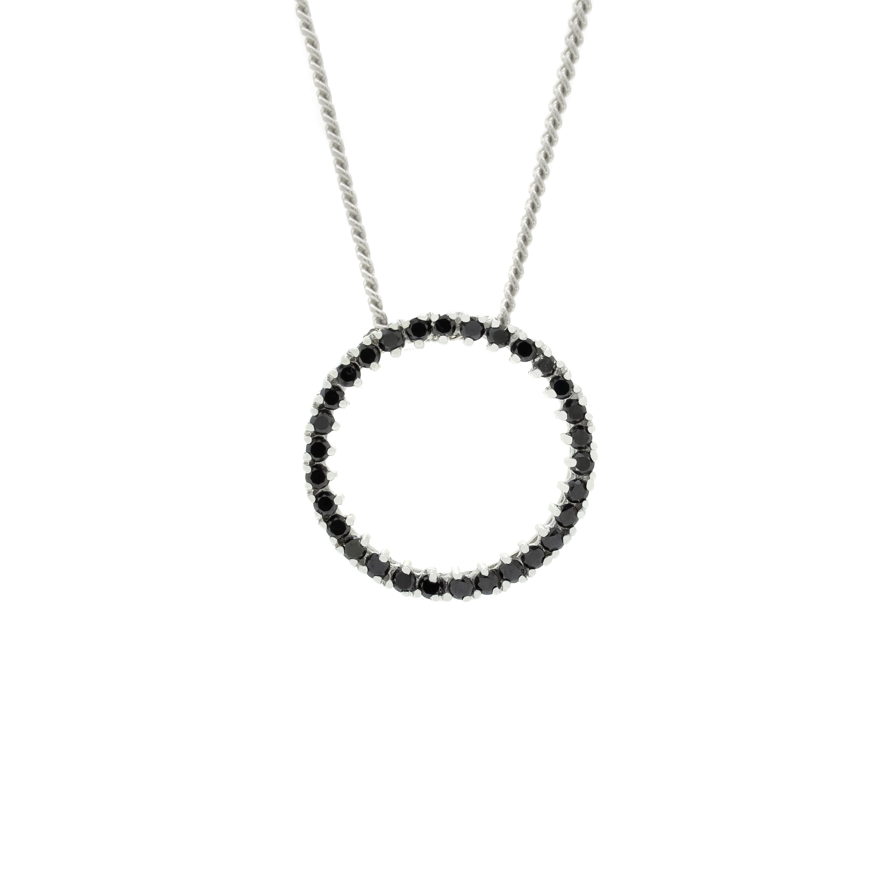 A product photo of a solid 9ct white gold and black diamond pendant suspended by a golden chain against a white background. The design is made up of 30 black diamond jewels arranged in a perfect hollow circle, reminiscent of an abstract ouroboros jewellery design. All of the diamonds are held in place by delicate golden claws.