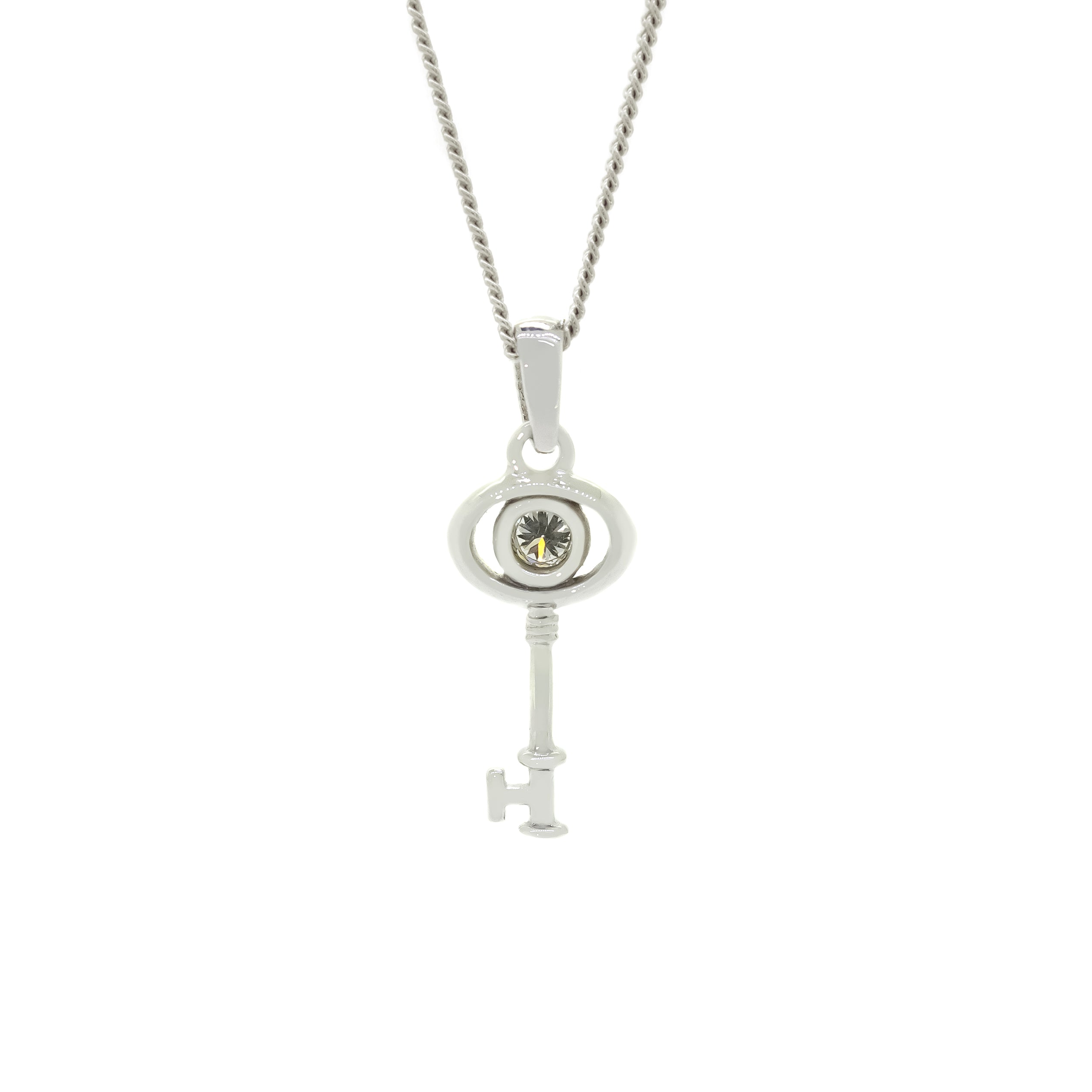 A product photo of a ceremonial diamond key pendant set in solid 9ct white gold. The design is dainty and left purposefully vague, so it may serve as a traditional 21st birthday present or as a key to something special to the wearer. The design consists of smooth and simple gold, with an oval-shaped loop framing a single round bezel-set diamond as the bow of the key, almost resembling an eye, while the rest of the key's design is simple and classic.