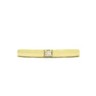 A product photo of a boldly minimalist wedding band made of solid 9k yellow gold sitting on a white background. The front is embedded with one little dazzling white diamond, which reflects multi-coloured light from its many facets.