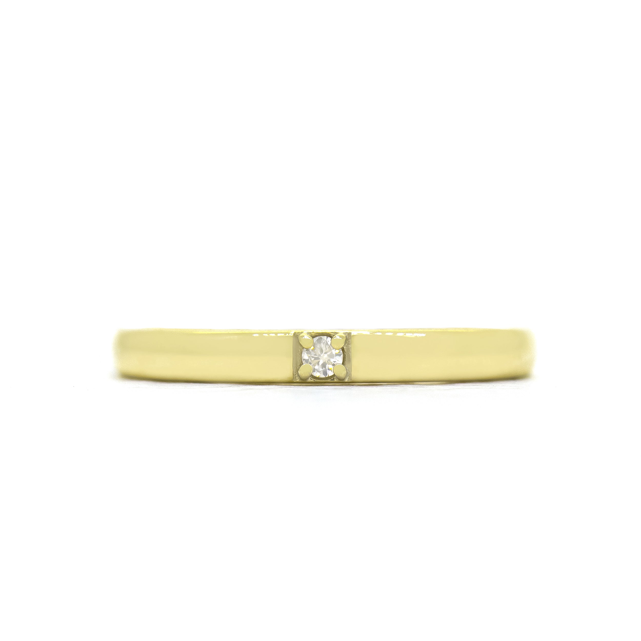 A product photo of a boldly minimalist wedding band made of solid 9k yellow gold sitting on a white background. The front is embedded with one little dazzling white diamond, which reflects multi-coloured light from its many facets.