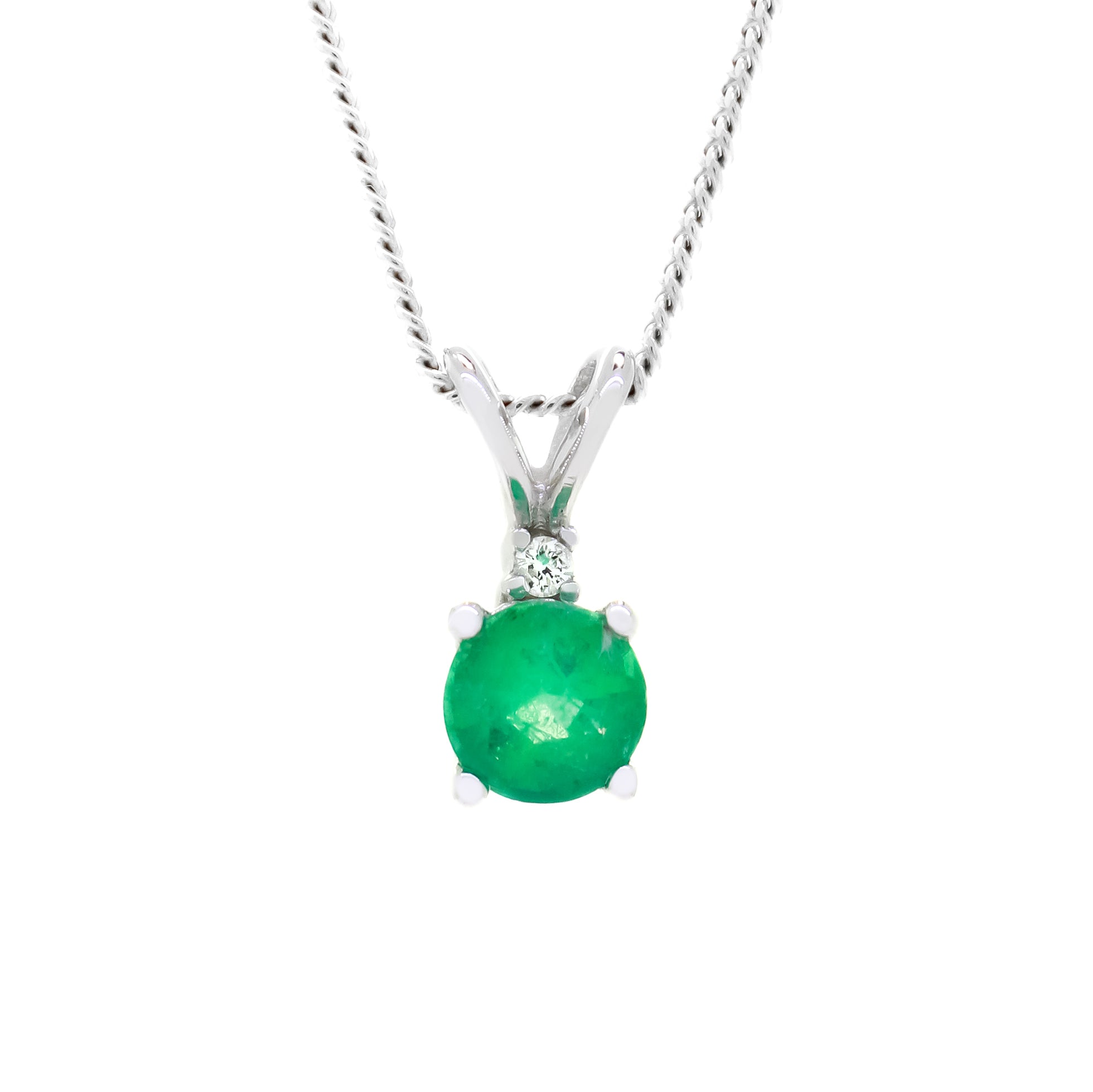 A product photo of a delicate, ornate emerald pendant with a single diamond accent suspended against a white background.