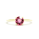 A product photo of a pink tourmaline solitaire riing in 9 karat solid yellow gold sitting on a white background. The deep pink gemstone measures 6mm across, and reflects breathtaking pink and magenta light from its many faceted edges - in stark contrast to its slim and minimalistic band and simple golden claws.