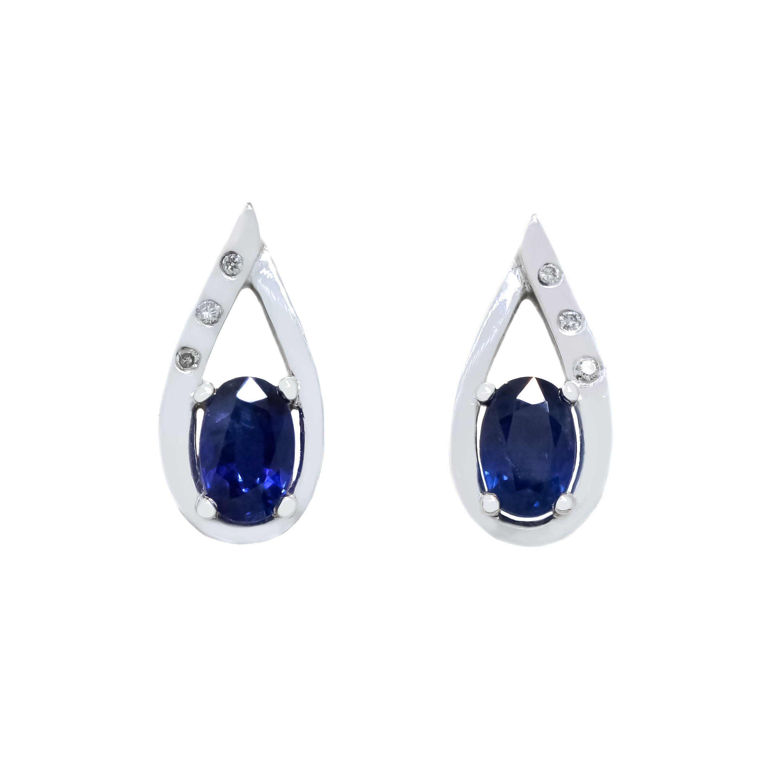 A product photo of a unique pair of sapphire and diamond earring studs with 6x4mm stones set in solid 9ct white gold. The deep, cool blue sapphire stones rest at the base of thick, golden frames in the shapes of teardrops, with the left side of each frame detailed with 3 tiny white diamonds, while the right side remains smooth. The two overlap where they meet at the very top.