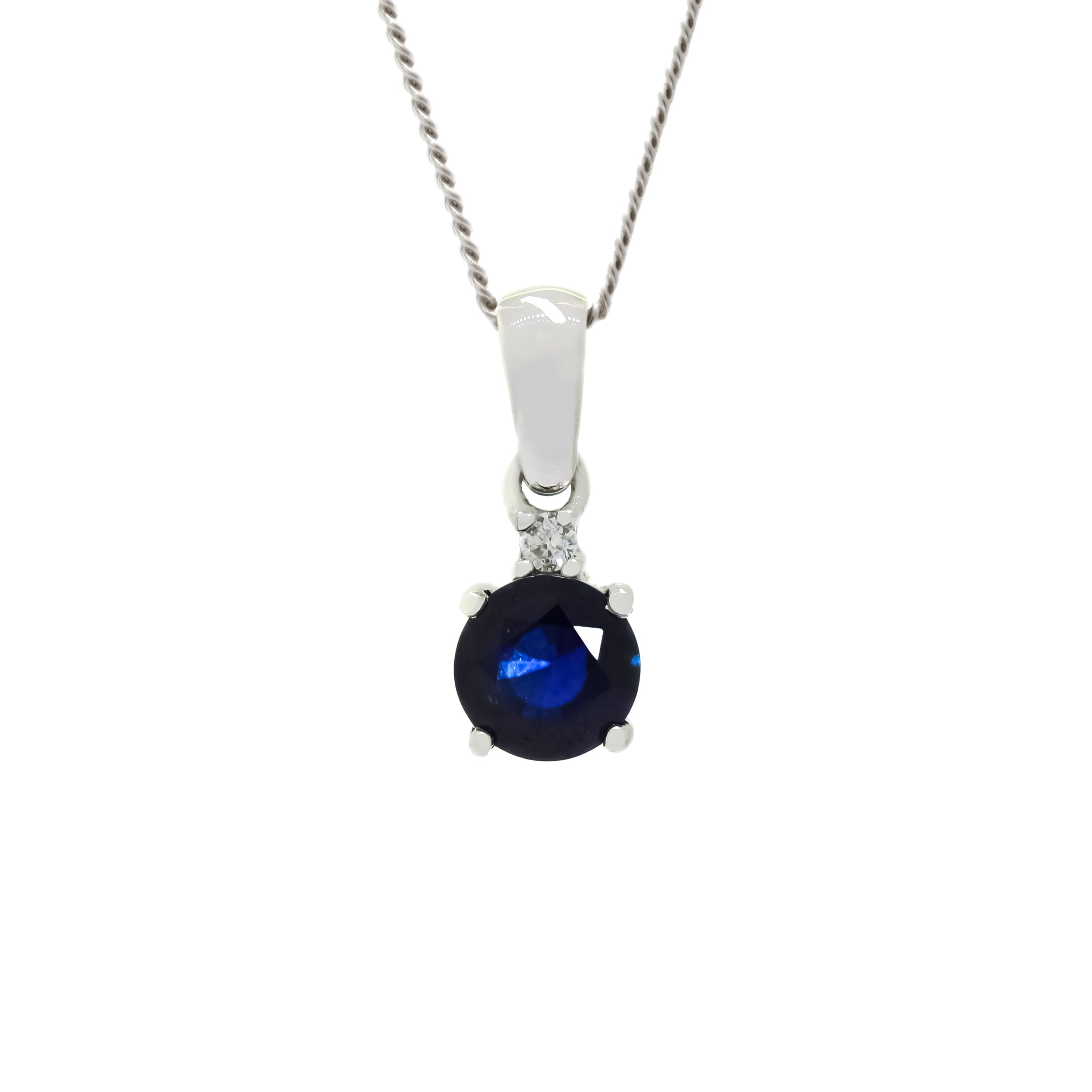 A product photo of a large, 6mm round sapphire and diamond pendant suspended by a 9ct white gold chain over a plain white background. The 1.10ct sapphire stone is a deep, dark blue, almost black in colour - but reflecting electric blue light from within.