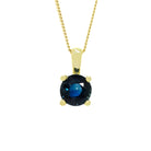 A product photo of a 9ct yellow gold fine sapphire pendant suspended by a gold chain against a white background. The round stone is held in place by 4 small claws, and reflects ocean blue hues from its many edges.