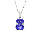 A product photo of a tanzanite and diamond pendant in 9k white gold sitting on a white background. The pendant is made up of two horizontal oval-shaped blue tanzanite stones, the bottom one being 7x5mm and the top being 6x4mm. The spaces between the two stones are filled with one small diamond on either side.