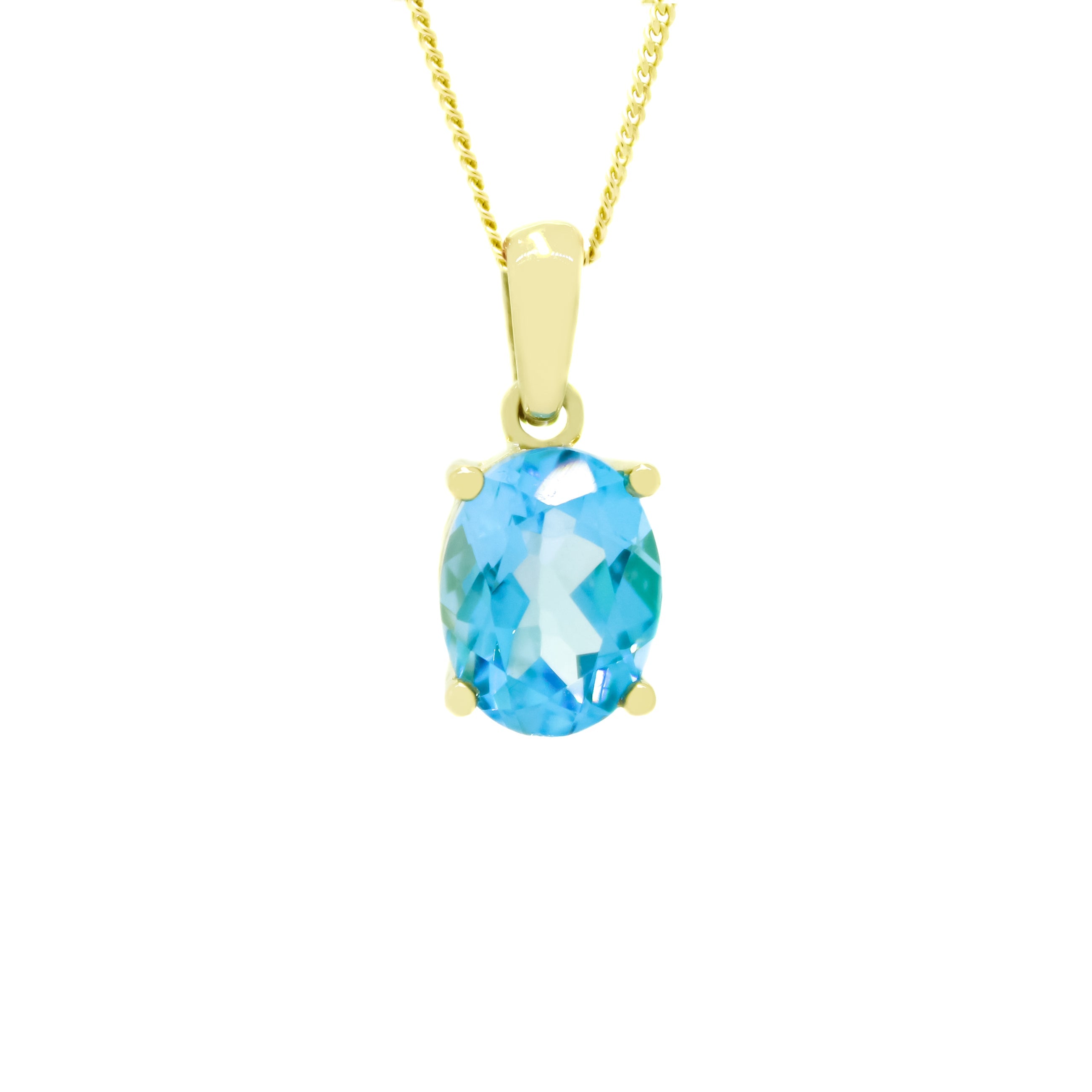 A product photo of a 9x7mm Oval blue topaz necklace in 9k yellow Gold suspended against a white background. The impressively large and deeply-coloured oval-cut stone is contrasted by its overall minimalistic design, 4 simple golden claws holding the gem in place. It is suspended by a simple gold chain. The stone is bright blue, reflecting tropical sky blue hues across its multi-faceted edges.