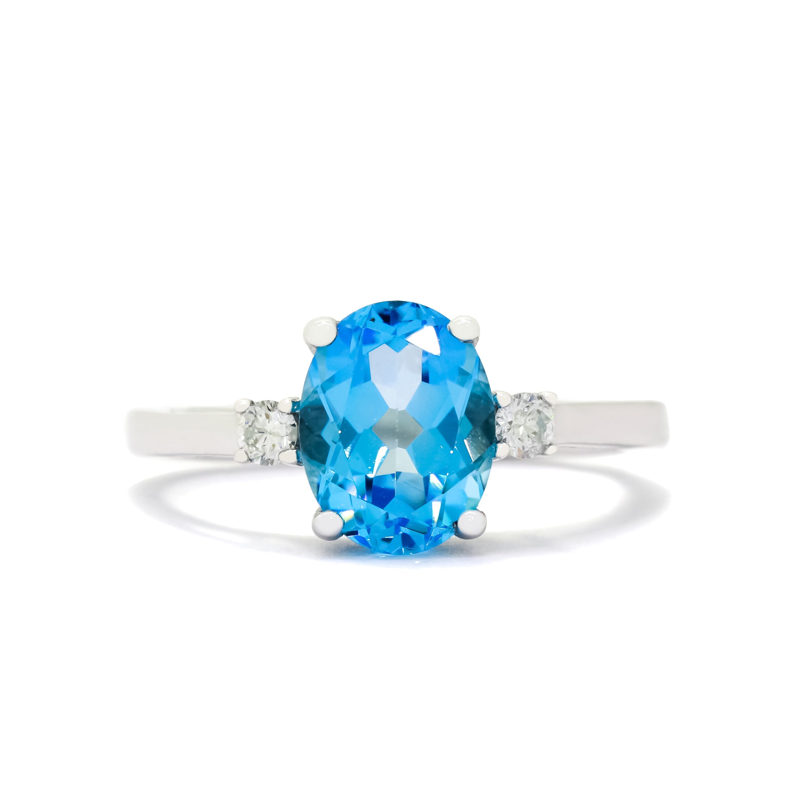 A product photo of a dainty and elegant white gold ring with a stunning trio of blue topaz and diamonds sitting against a white background. The large centre stone is hugged by two smaller circular white diamonds on either side.