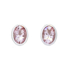 A product photo of a pair of morganite earrings in 9ct white gold sitting on a white background. The 7x5mm morganites are framed in a thick layer of white gold in a bezel setting.