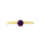 A product photo of a delicate yellow gold stacking ring with a tiny, claw-set amethyst in the centre sitting on a white background. The band is slim and thread-like, with the focus drawn to the petite 4mm glinting amethyst gemstone.