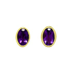 A product photo of a pair of amethyst earrings in 9ct yellow gold sitting on a white background. The fine 6x4mm amethyst jewels are framed in a thick layer of yellow gold in a bezel setting.